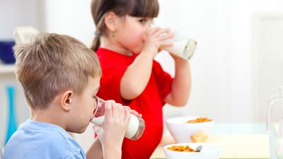 Zwei Kinder trinken Milch aus Gläsern